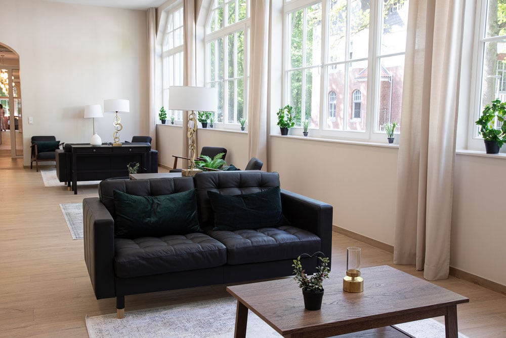 Hochwertiges Wohnambiente mit stilvollem Couchbereich und großen Fensterfronten, die viel Tageslicht in den Wohnraum bringen, perfekt für moderne Inneneinrichtung und gemütliches Wohnen.