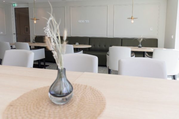 Moderne Gastronomie mit stilvollem Interieur, weiße und graue Sitzgelegenheiten, dekorative Vasen und ansprechende Beleuchtung, ideal für Restaurant- und Café-Design, hochwertiges Wohn- und Gastgewerbeambiente.