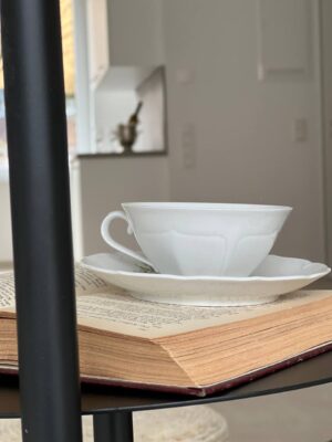 Elegante weißes Teegeschirr auf einem geöffneten Buch, stilvolle Inneneinrichtung, modernes Design, hochwertige Porzellanwaren, ansprechende Dekoration für modernes Wohnen.