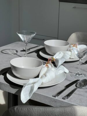 Elegant Esstisch Dekor mit weißem Geschirr, Gläsern und Besteck im modernen Küchenambiente – perfekte Gestaltung für stilvolles Wohnen.