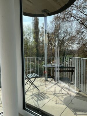 Gemütlicher Balkon mit moderner Möbelgestaltung, Blick auf grüne, lebendige Natur, ideal für Entspannung im Freien bei schönem Wetter.