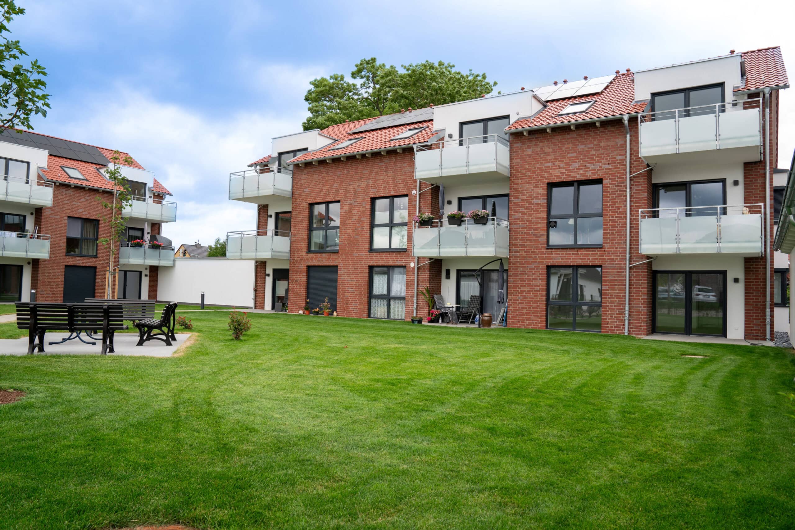 Moderne wohnanlage mit grünem garten und balkon, energieeffiziente hausfassade von Hahne Wohnen in Deutschland.